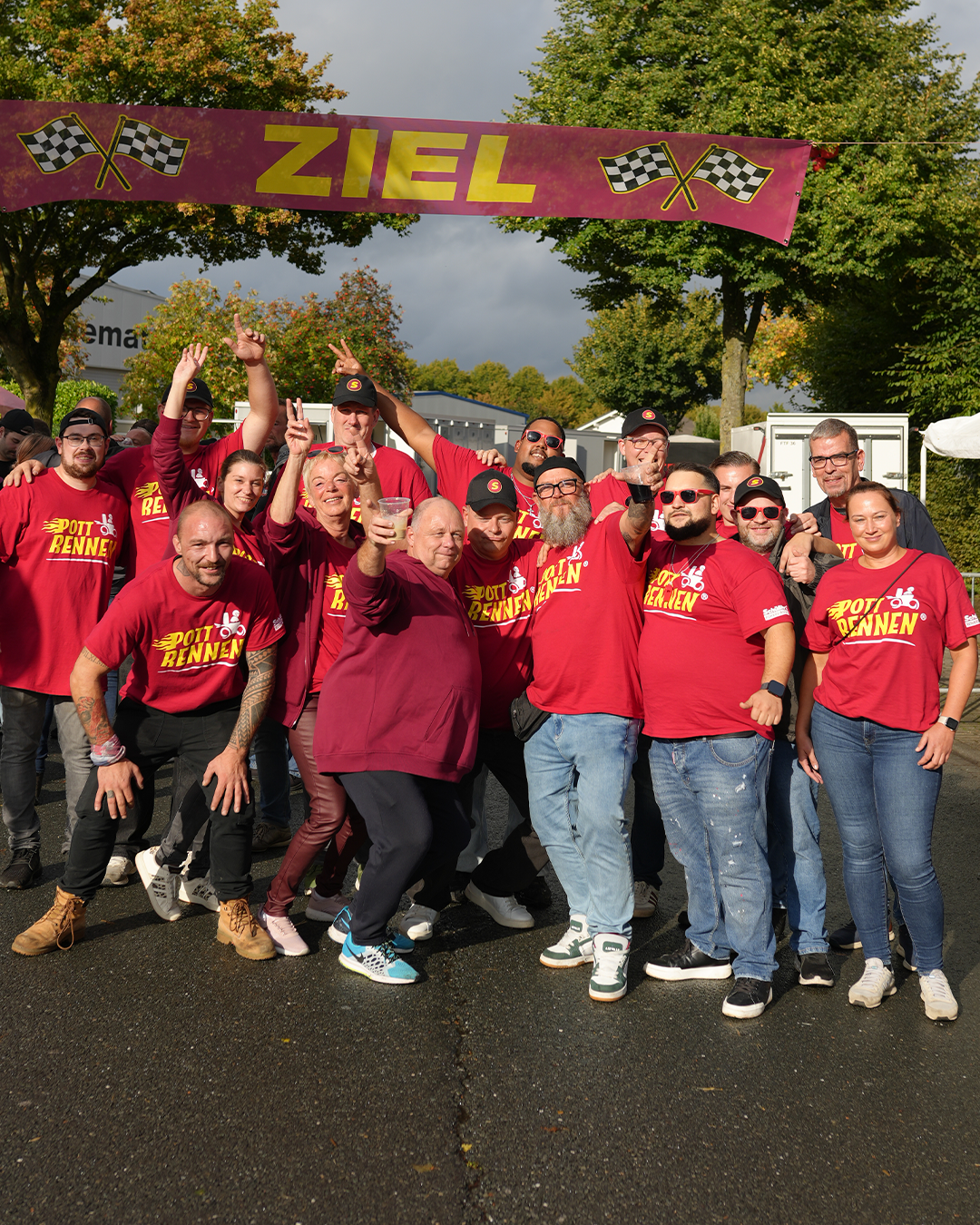 Jubelndes Team in roten Pottrennen-Shirts am Ziel-Banner beim Pottrennen 2026